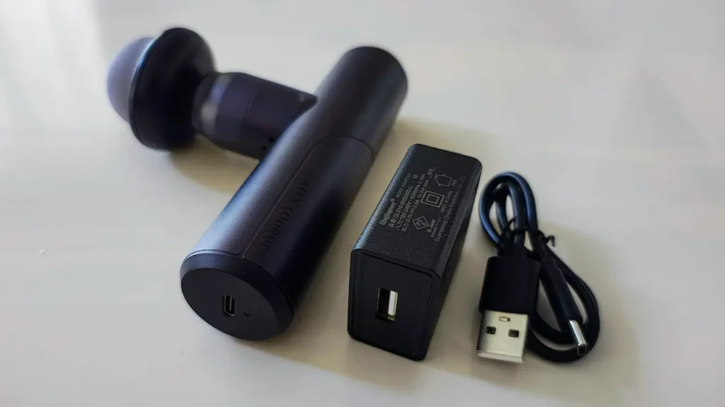 黒いマッサージガンと充電器とケーブル